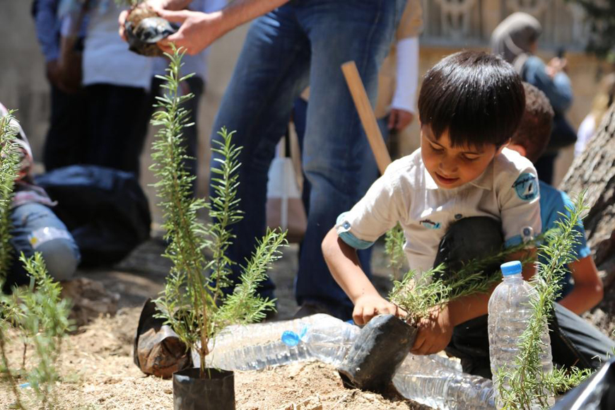 A boy plants an evergreen sapling at Heina Garden in Jabal Al Natheef during a recent celebration marking the 10th anniversary of the Ruwwad Al Tanmeya NGO (Photo courtesy of Ruwwad Al Tanmeya)